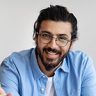 Ritratto di un uomo sorridente con i capelli neri raccolti e la barba ben curata